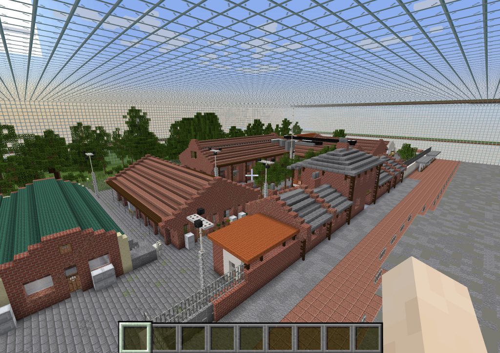 Screenshot of the virtual site of Cattle Depot in Minecraft. Buildings in digital red brick showing the Cattle Depot, with grey roof tiles and trees in the courtyard at the centre. 
Behind the Cattle Depot is a small park with trees. And to the left of Cattle Depot is another red brick building with a dark green roof. Buildings a re a mixture of one and two storeys in height.
A grid structure was built in the sky above the site by the previous resident artist. This forms a matrix against the blue sky.