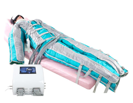 A person lying down wearing a sky blue and grey padded full body suit with several grey straps on the torso and legs. They have some kind of thick black and white mask over the top half of their face and they are lying on a pink hospital bed which seems to be floating in mid air. There is a plastic tube coming from the center of the torso attached to some kind of white gadget which is on the bed. In the foreground their is another floating white appliance with several grey wires coming out of it. It has a black screen with blue text on it. The sleeves and trousers have no hands or feet coming out of them and the entire image has an eery futuristic quality. 