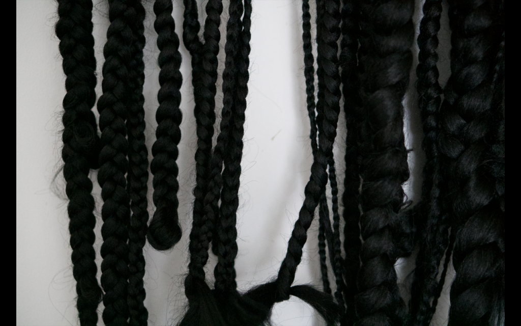 A white background with black braided hair of different thicknesses overlaid and layered over each other.