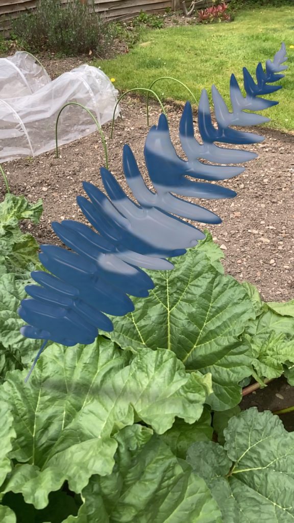 One of Anna Atkins leaves created in Adobe Illustrator and Vectary with the Anna Atkins print used as a material. Photograph taken over rhubarb leaves. 