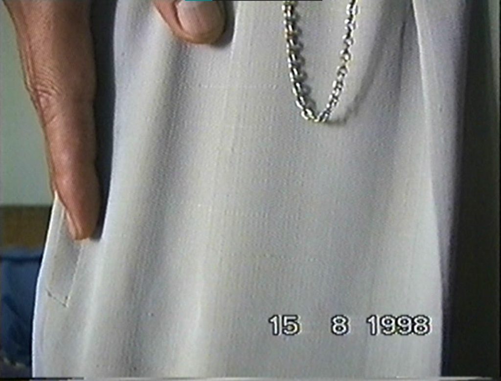White trousers with a silver chain covering up the frame of the video.