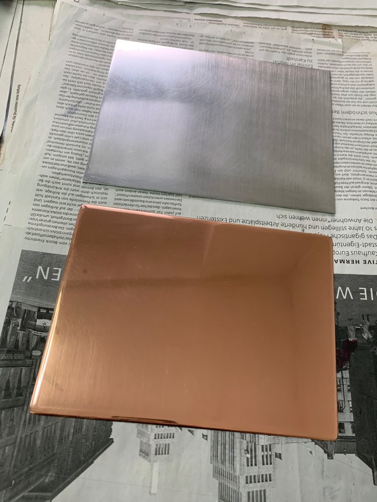 a copper plate and an aluminum one, same sizes on some newspaper. The copper one is more rounded and shiny, the aluminum is sharp edged and opaque.