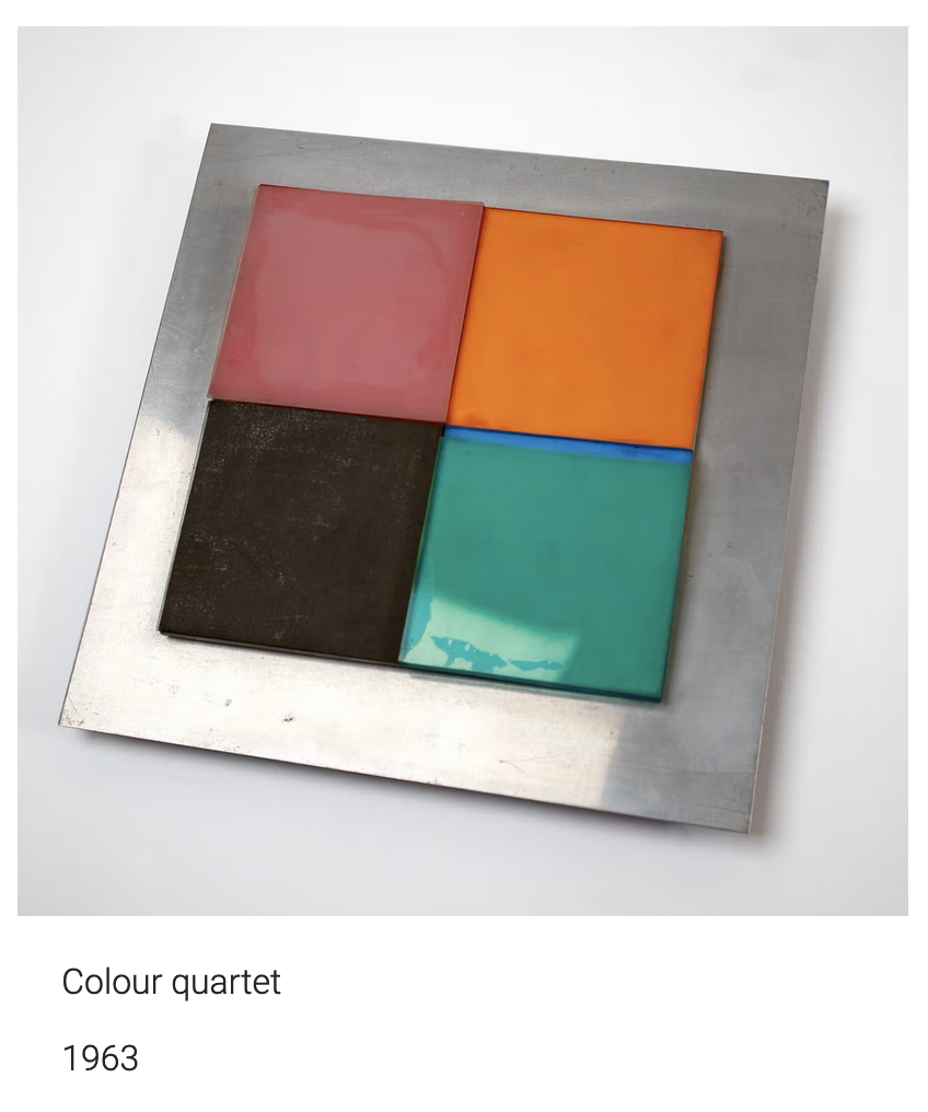 This is an image of an artwork called Colour Quarter by Gillian Wise produced in 1963. It is a square metal piece with four smaller coloured squares within in. A soft red, a brown-black, an almost turquoise green and an orange. The work has an industrial feel mixed with a playful style. 