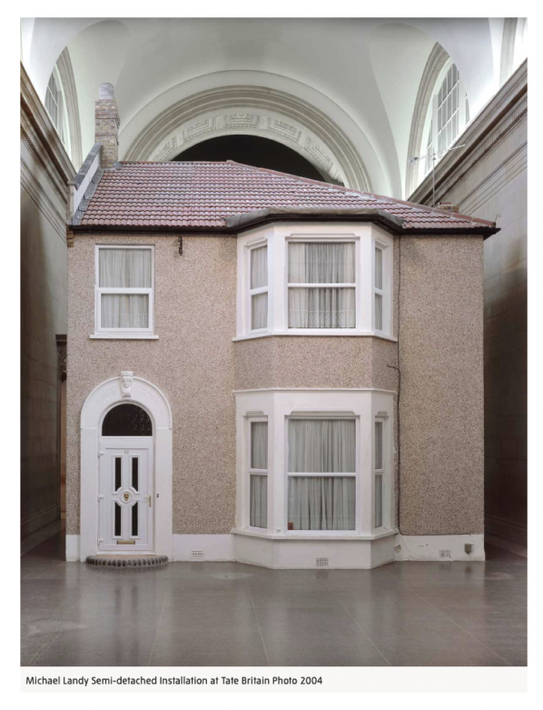 This image is a photograph of Michael Landy's artwork 'Semi-detached' at Tate Britain in 2004. The work is an exact replica of his father's home in Ilford. It is a life-size semi-detached house with a typical 1970s pebble-dash exterior, white bay windows and a white door with brass handle and knocker. The welcome invites the viewer and marks the threshold of interaction. 