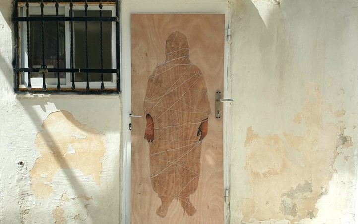 A silhouette image of a woman with brown hands showing on a door. 