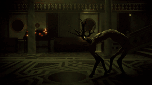 An animated gif of a the inside of a dark and gloomy catholic church. Candle offerings are burning in the background. The floor is a beautiful mosaic. A strange creature moves awkwardly forwards. It seems to have deer legs and deer antlers, but no head, and possibly the body of a humanoid with their back arched