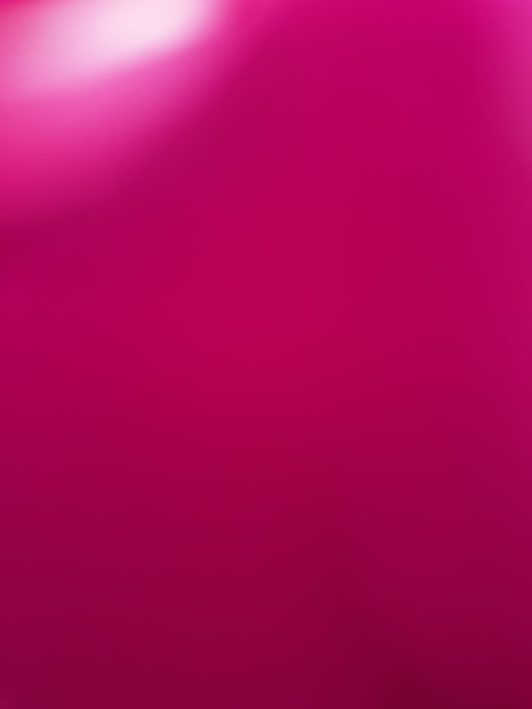 A digital photograph (portrait, colour), of what looks like some abstract image in shades of pink and red. There is a bright glare of white in the top left corner of the image that spills out into bright pink fading into a wash of reds and deeper reds towards the bottom of the image. It is not at all clear what the image is depicting; shape and colour are its only feature.