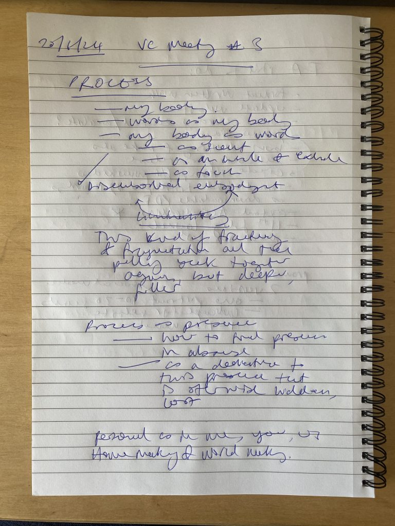 A digital photograph (portrait, colour), of what looks like a ring bound ruled notebook with a page filled with a scrawl of handwriting in blue biro. The handwriting isn't clear what the text says, it is loose, loopy and expressive in its energy. Headings such as "VC meeting #3", "PROCESS" and "process as presence" are just about legible, but it is hard to make out. 