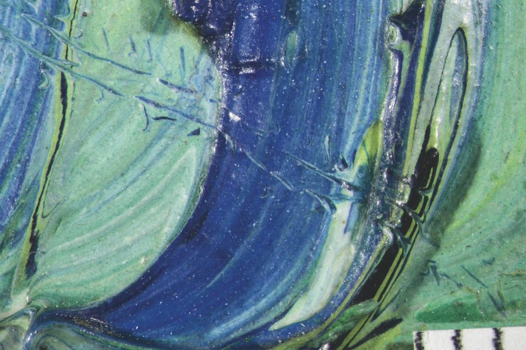 A close up of abstract colours, light blue, dark blue and shades between. It is as if an insect has been drawn across these thick paints, fine tracks left behind by his passage.
