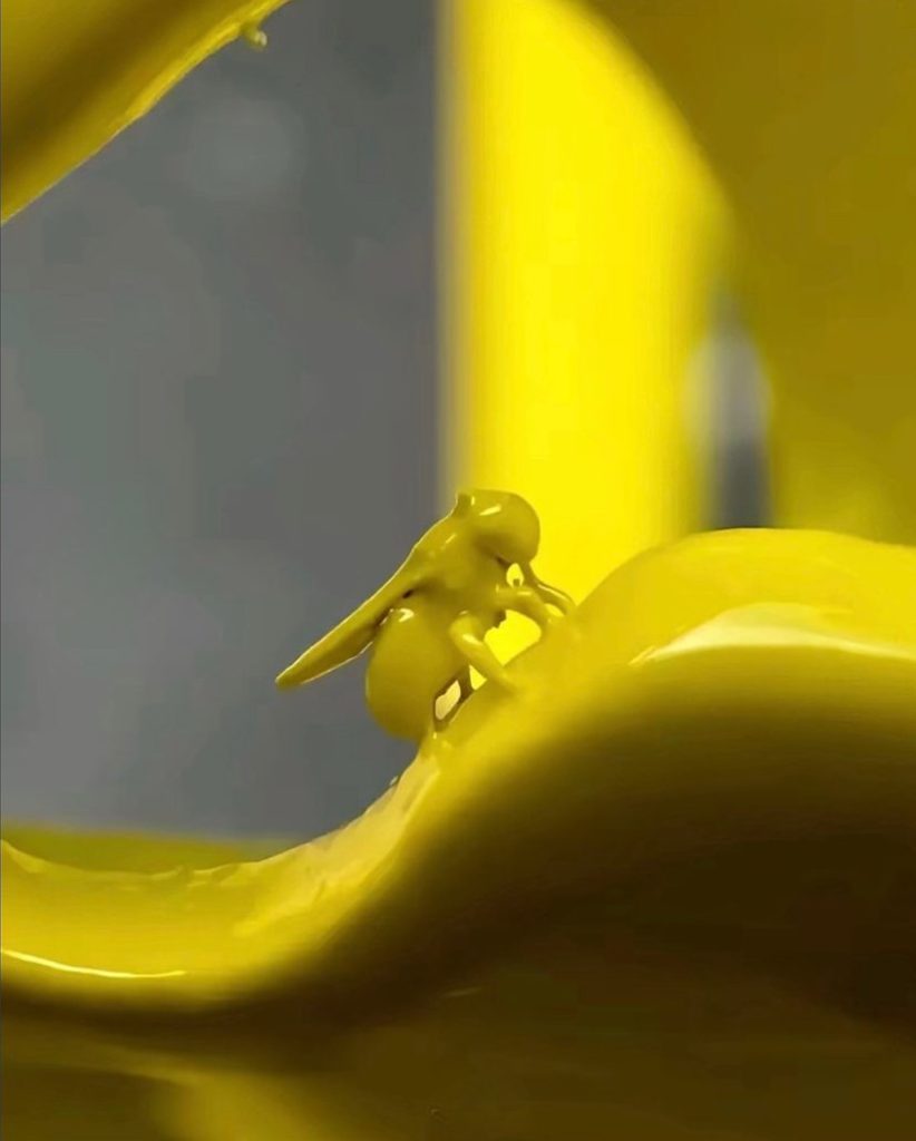 Further close up of the previous image, a fruit fly is forever moulded to a bright yellow structure as it has been covered in its yellow finish. The entire body is visible in the middle of the image, wings, legs and all.